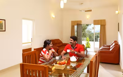 A couple enjoying a warm cup of tea at The Fog Resort in Munnar, with misty hills and scenic landscapes creating a tranquil and romantic ambiance